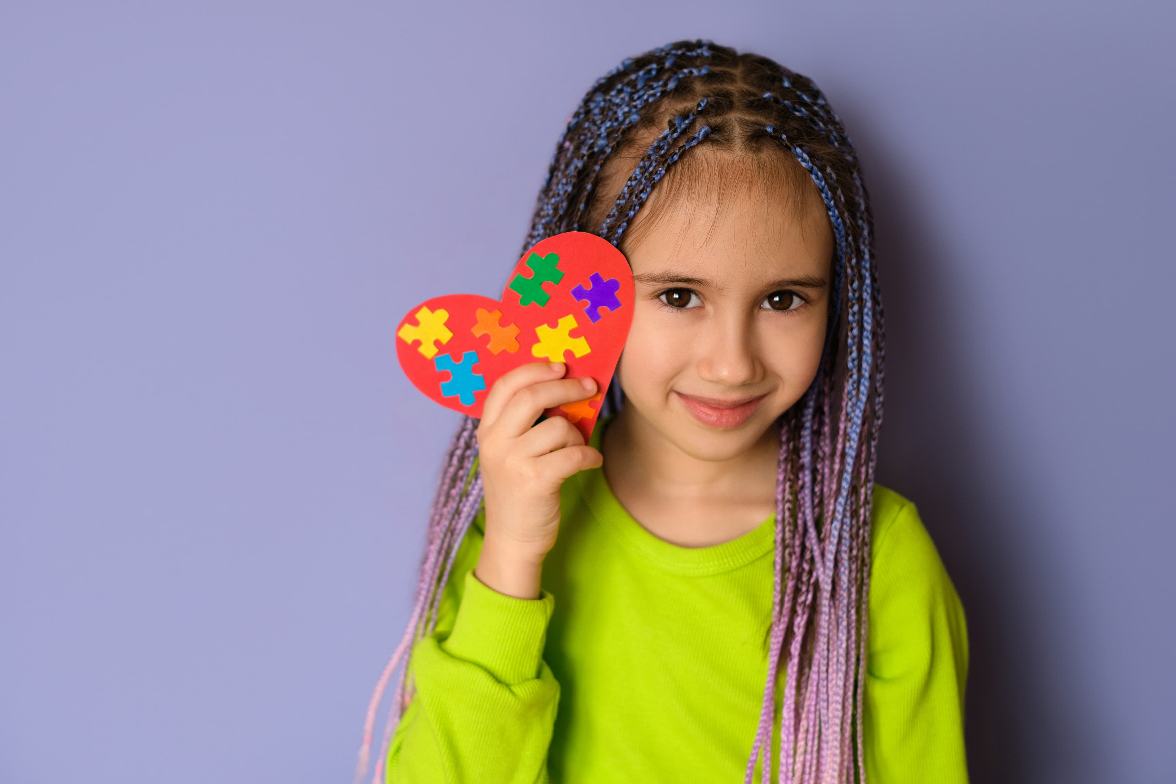 Child holding a colorful puzzle heart